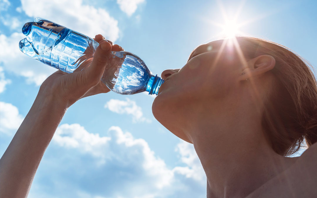 Woman drinking water from a bottle on a sunny day