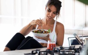 Pretty young woman with healthy skin eating a nutritious meal in her kitchen