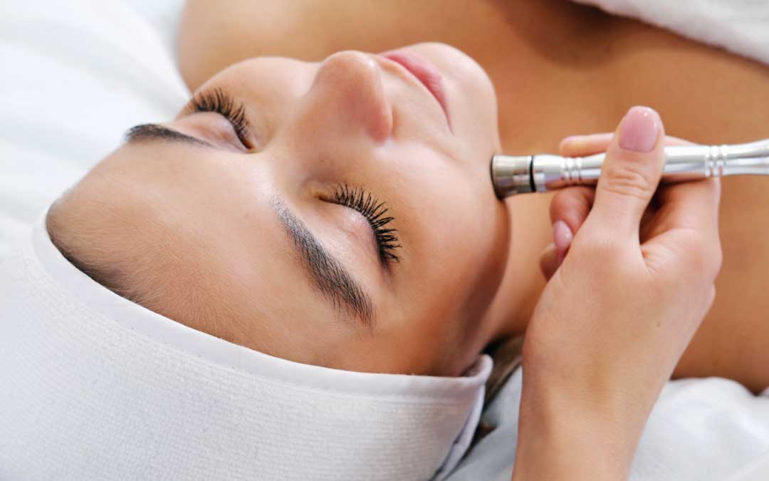 Women getting microdermabrasion treatment to her face