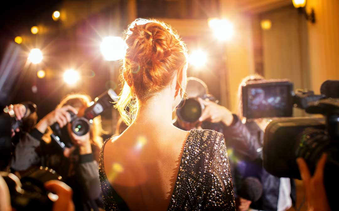 Female celebrity walks the red carpet while cameras flash